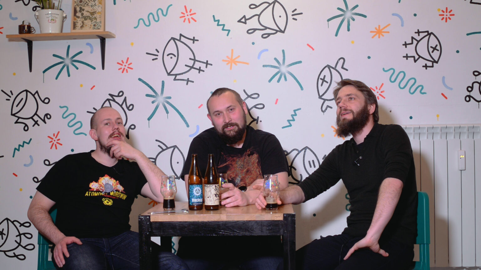 Od lewej: Łukasz Szymański, Artur Karpiński i Grzegorz Stachurski siedzą przy stoliku w Dżungla Cafe, na stole mają 2 butelki piw i 3 szklanki.